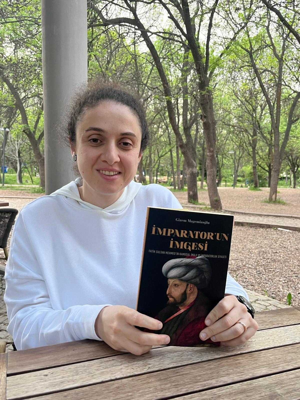 A person sitting at a table holding a book

AI-generated content may be incorrect.