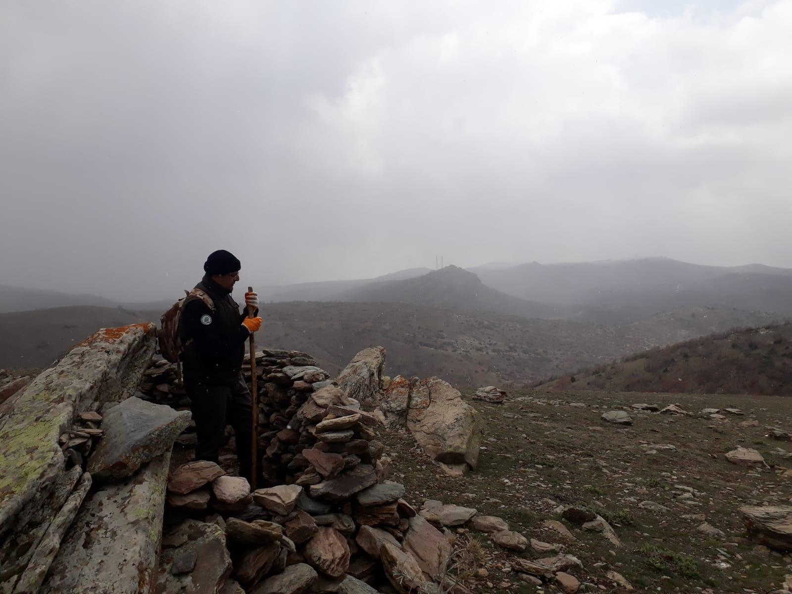 A person standing on a rocky hill
Description automatically generated